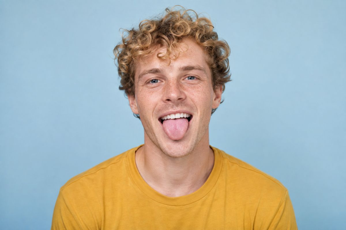AI tongue out effect on a curly-haired man wearing a yellow shirt